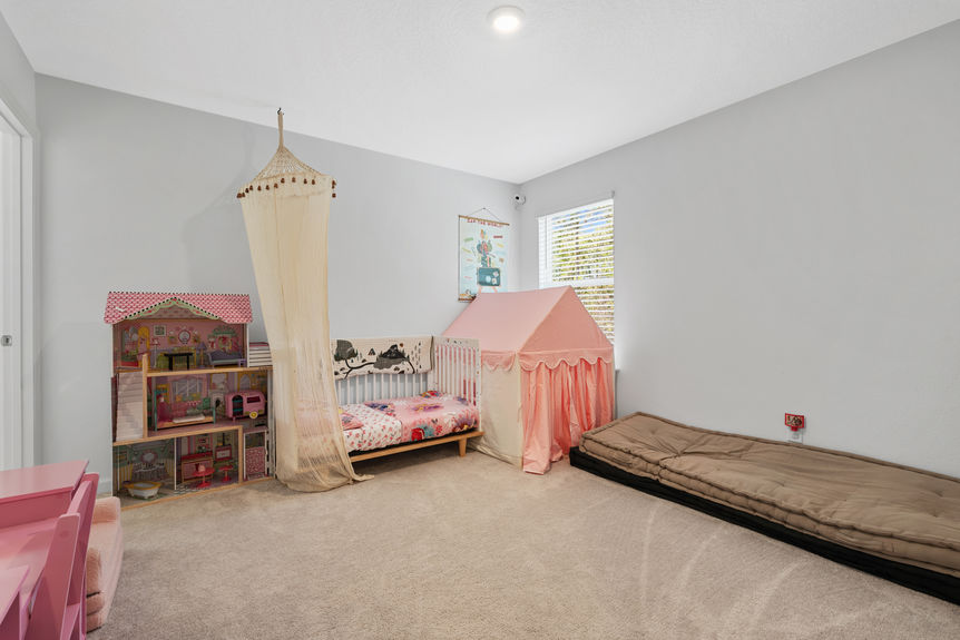 Guest bedroom with large window, neutral walls, and plush carpeting in St Augustine Lakes home