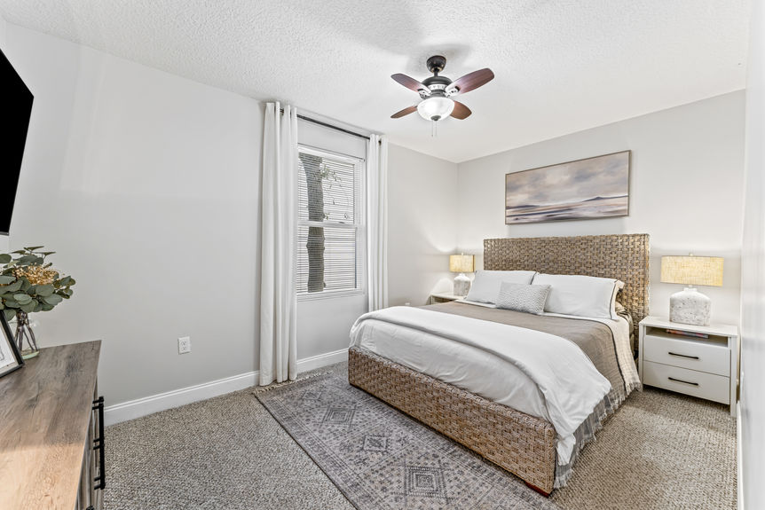 Bright and airy primary bedroom with large windows, wood flooring, and neutral décor in a St. Augustine home