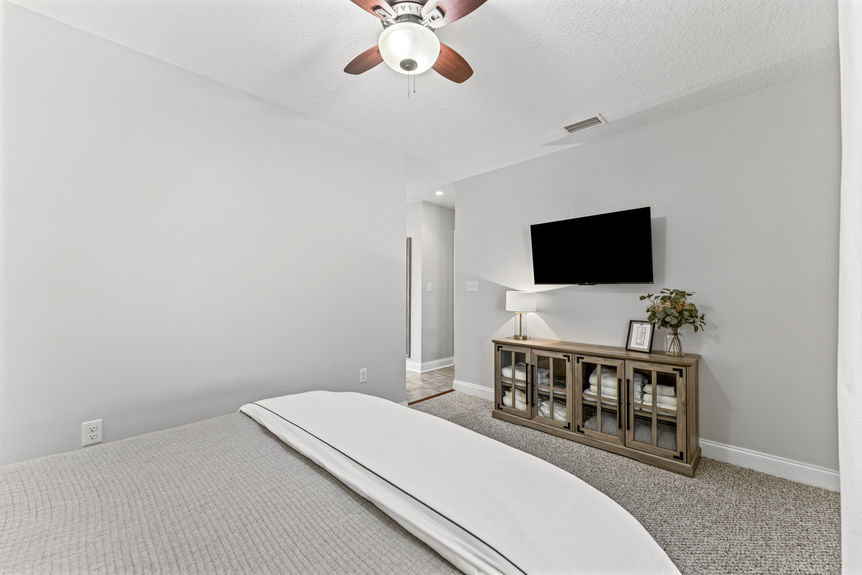 Bright and airy primary bedroom with large windows, wood flooring, and neutral décor in a St. Augustine home