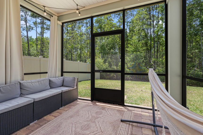 Outdoor covered patio with seating, hammock, and sliding glass doors leading to the backyard and preserve in St Augustine