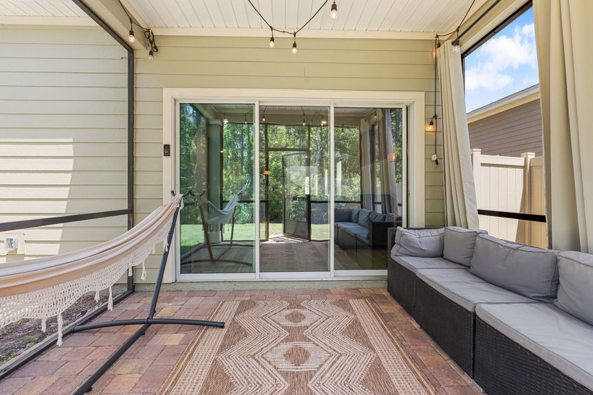 Outdoor covered patio with seating, hammock, and sliding glass doors leading to the backyard and preserve in St Augustine