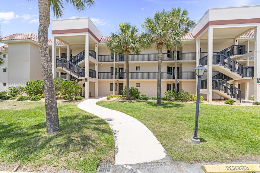 Front view of Ocean Village Club condo building with palm trees and walkways