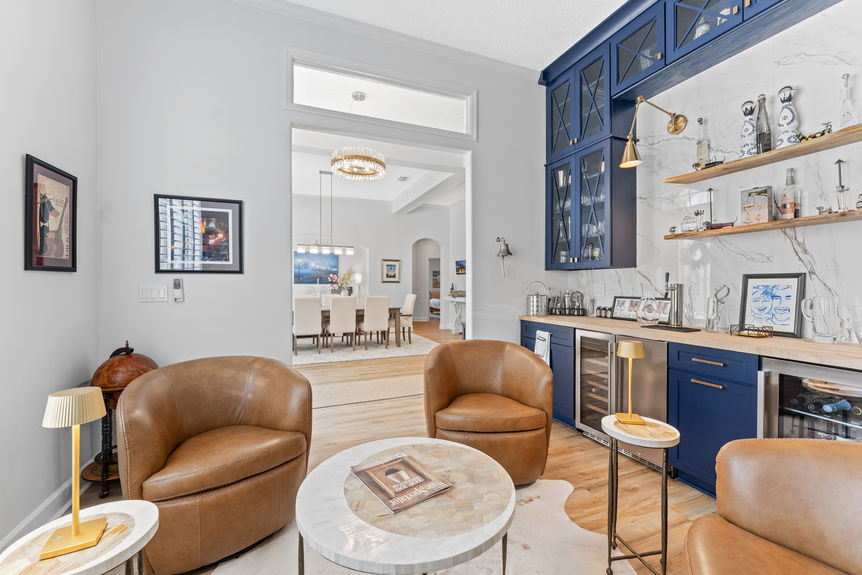 Custom home bar with navy cabinets, leather chairs, and wine storage in a St Augustine house