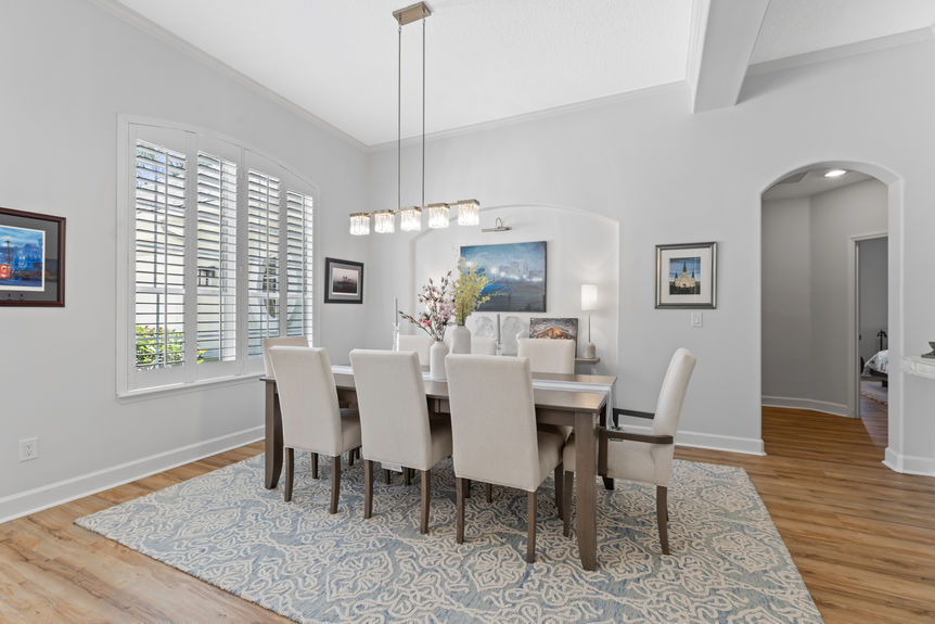Bright dining room with a long table, modern chandelier, and natural light from large windows