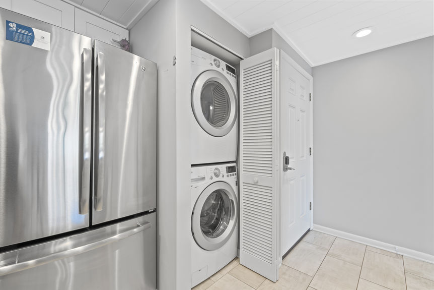 Stackable washer and dryer next to stainless fridge in condo unit