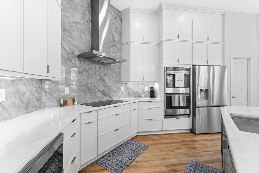 Detailed view of modern kitchen with cooktop, double oven, and marble finishes