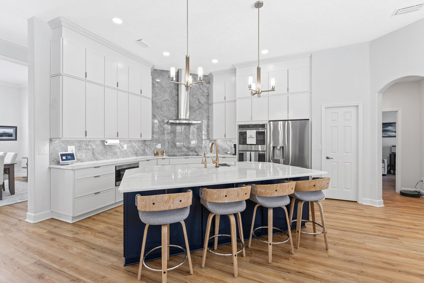 Modern white kitchen with marble backsplash, waterfall island, and bar seating