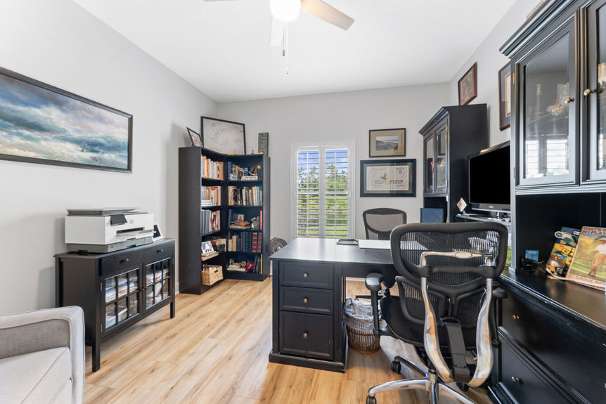 Home office with black desk, built-in cabinetry, and window view in a St Augustine Florida home