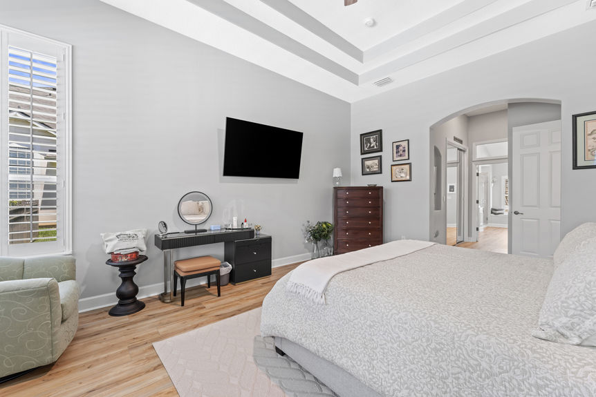 Master bedroom with tray ceiling, large windows, and cozy sitting area in a St Augustine Florida home