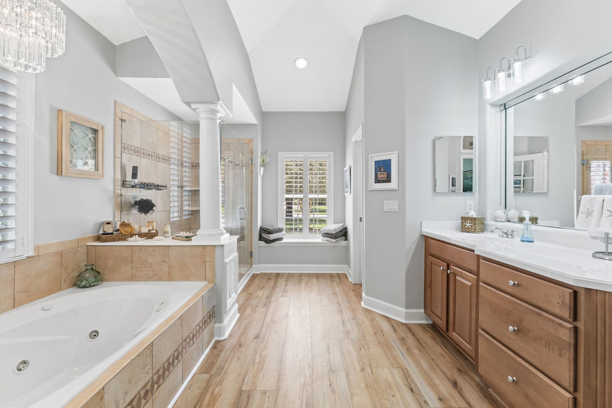 Elegant master bathroom with soaking tub, glass walk-in shower, double vanity, and natural light