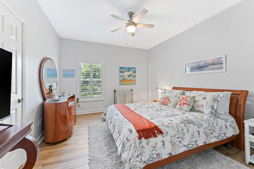 Bedroom with colorful ocean-themed bedding, wood furniture, and window view