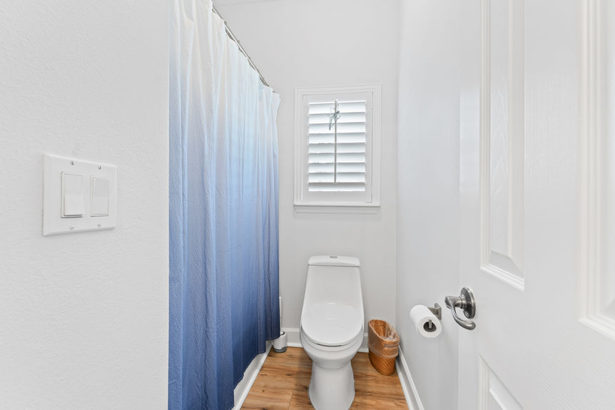 Bathroom with double sinks and view into guest bedroom with beach decor