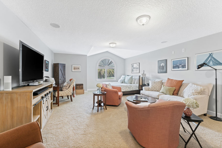 Bonus room showing entertainment setup, staircase, and bathroom entry