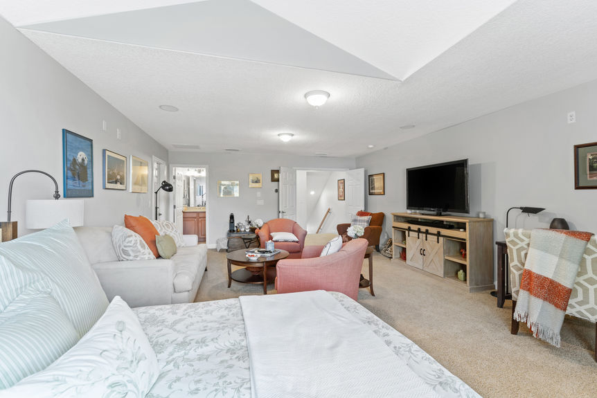 Bonus room showing entertainment setup, staircase, and bathroom entry