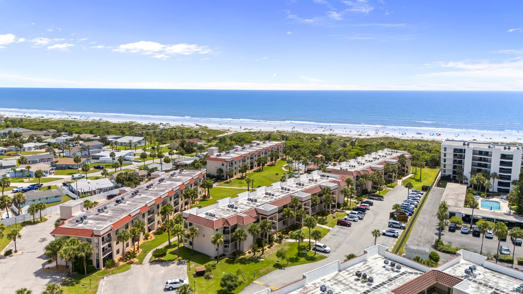 Aerial view of Ocean Village Club condo building with palm trees and walkways