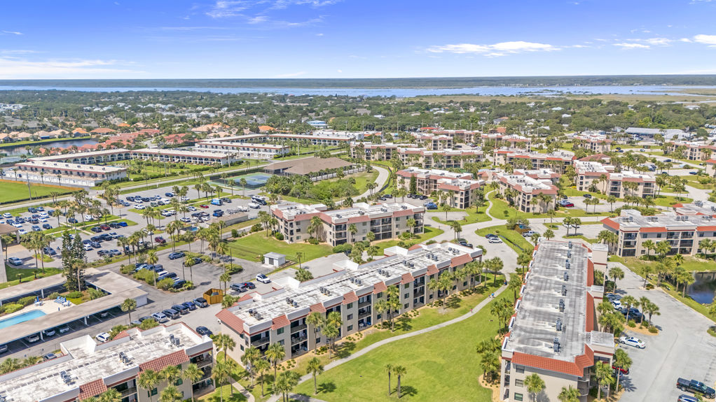 Aerial view of Ocean Village Club condo building with palm trees and walkways