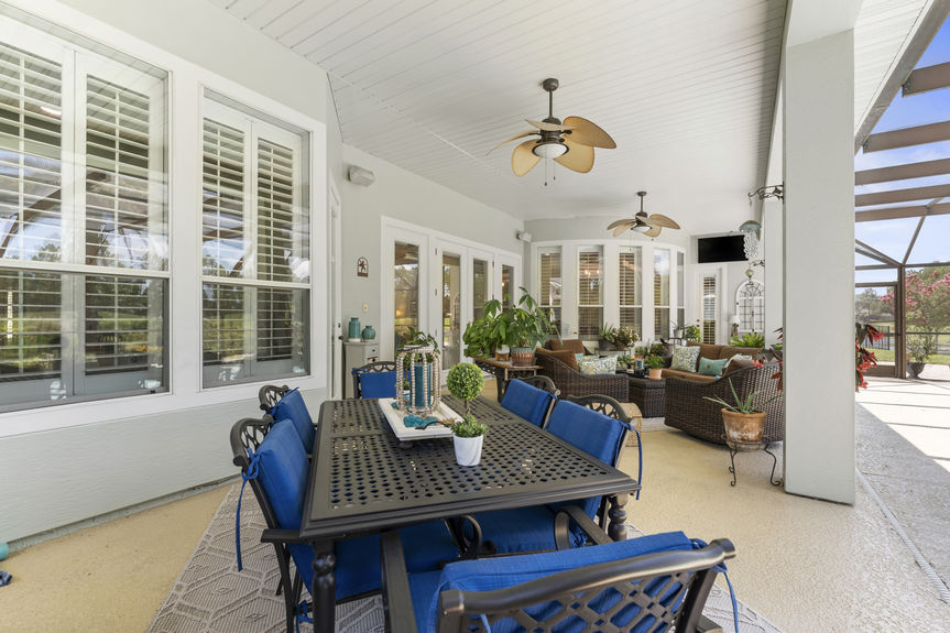 Screened lanai with dining table, ceiling fans, and seating area in a St Augustine Florida home