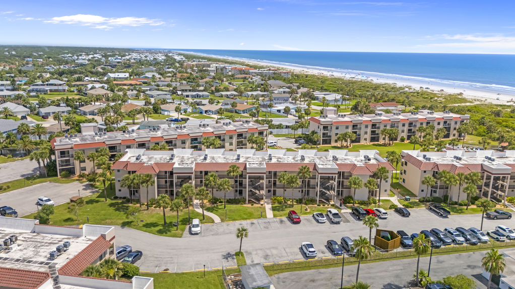 Aerial view of Ocean Village Club condo building with palm trees and walkways