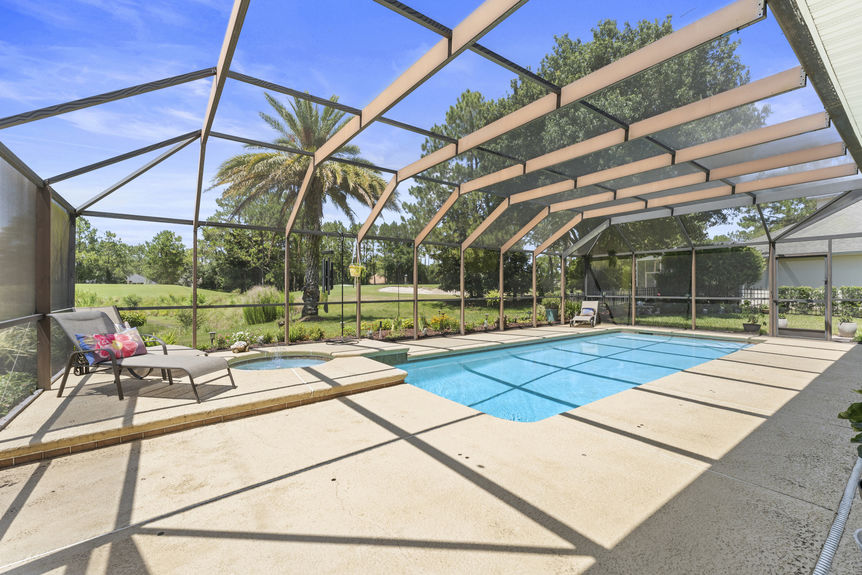 Sparkling blue pool with spa and screened enclosure overlooking water and greenery