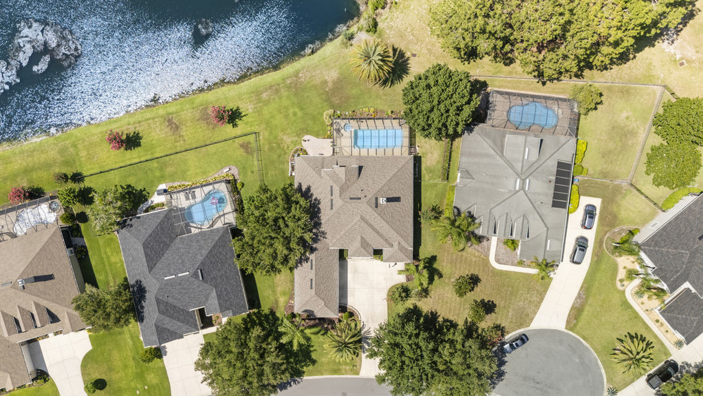 Overhead view of home with screened lanai and large yard with mature trees and landscaping