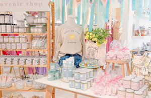 Pastel-themed souvenir shop display in St. Augustine featuring candles, mugs, skincare, and a “Meet Me for Coffee” sweatshirt on a mannequin