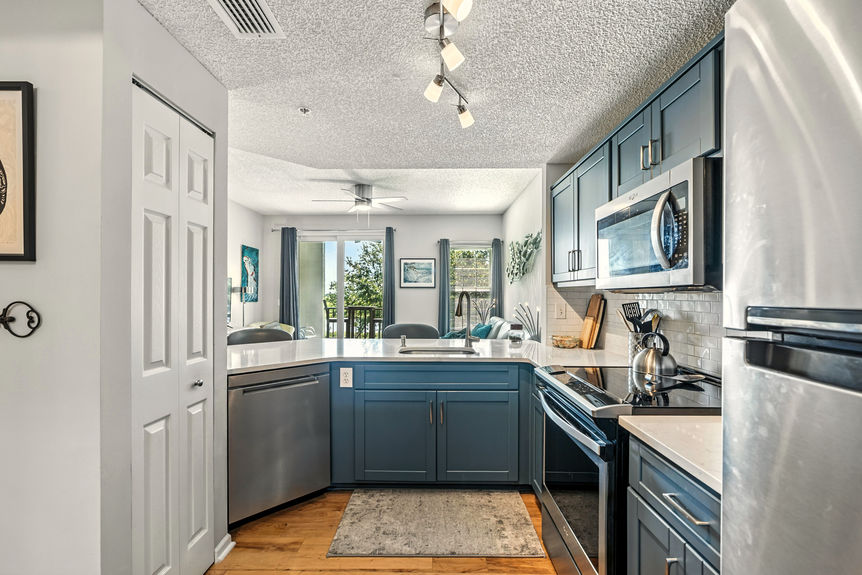 Modern kitchen with quartz countertops, stainless steel appliances, and blue cabinetry