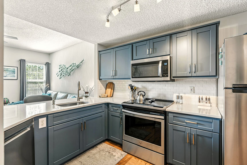 Modern kitchen with quartz countertops, stainless steel appliances, and blue cabinetry