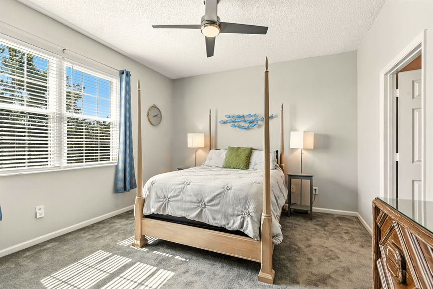 Bright guest bedroom with large window, modern ceiling fan, and neutral decor in Las Palmas condo, St. Augustine, FL