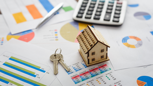 Miniature house and keys on top of real estate market charts and graphs representing St. Augustine FL housing data.