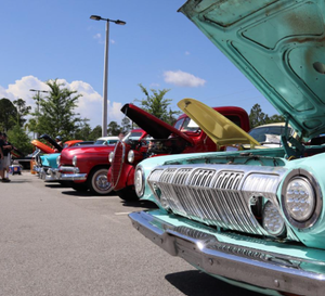 Row of colorful classic cars with hoods open at the Cruisers Car Club Cruise-In, Classic Car Museum of St. Augustine.