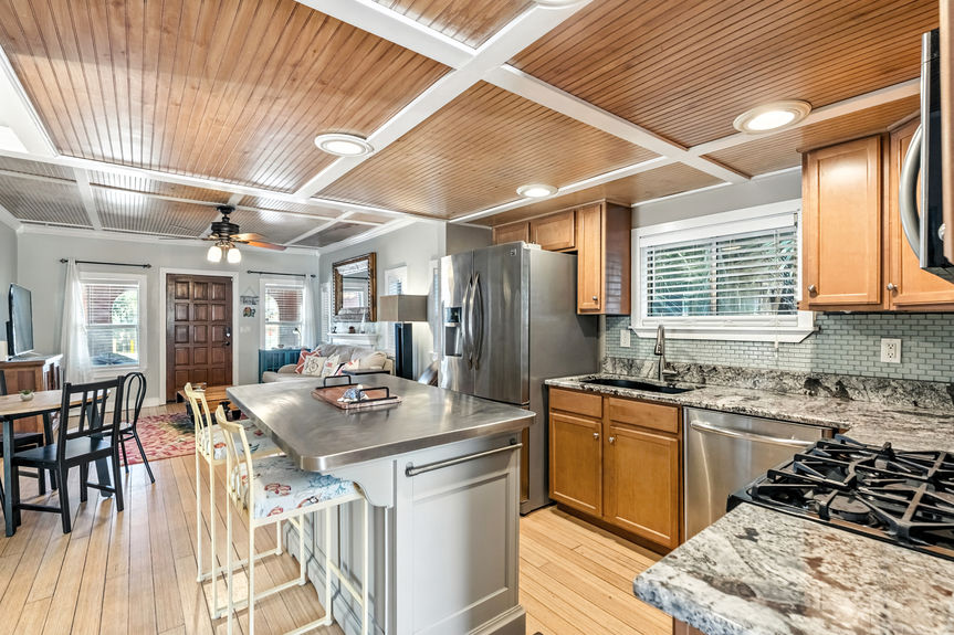 Contemporary kitchen with stainless steel appliances, wood cabinets, granite countertops, and center island in a St Augustine Florida home for sale.