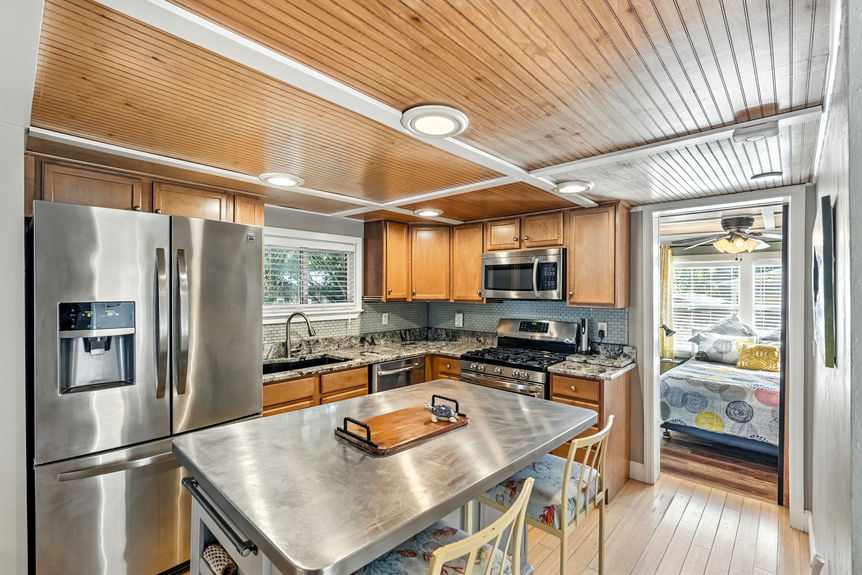 Contemporary kitchen with stainless steel appliances, wood cabinets, granite countertops, and center island in a St Augustine Florida home for sale.
