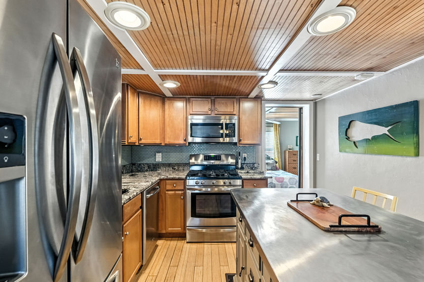 Contemporary kitchen with stainless steel appliances, wood cabinets, granite countertops, and center island in a St Augustine Florida home for sale.
