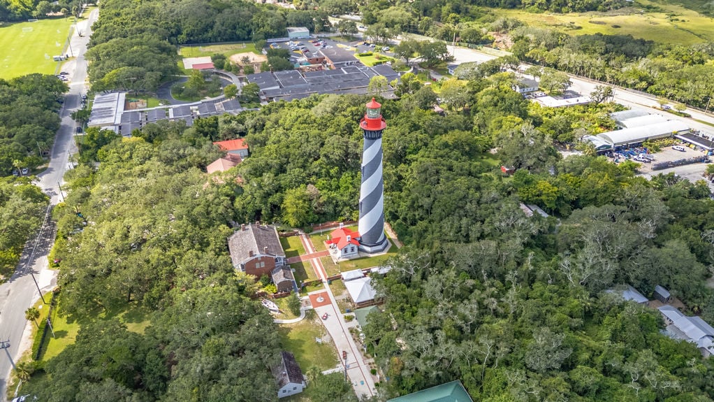 Drone view of St Augustine Florida featuring the historic lighthouse, waterfront, and coastal neighborhoods.