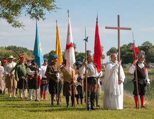 Historical reenactment of St. Augustine’s Founders Day with costumed participants carrying flags and a cross during a ceremony