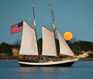 Schooner Freedom sailing under a full moon with American flag, St. Augustine FL