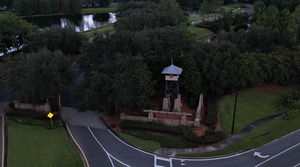 Aerial view of Heritage Landing entrance in St. Augustine, Florida, with landscaped greenery, lake, and welcoming neighborhood sign.