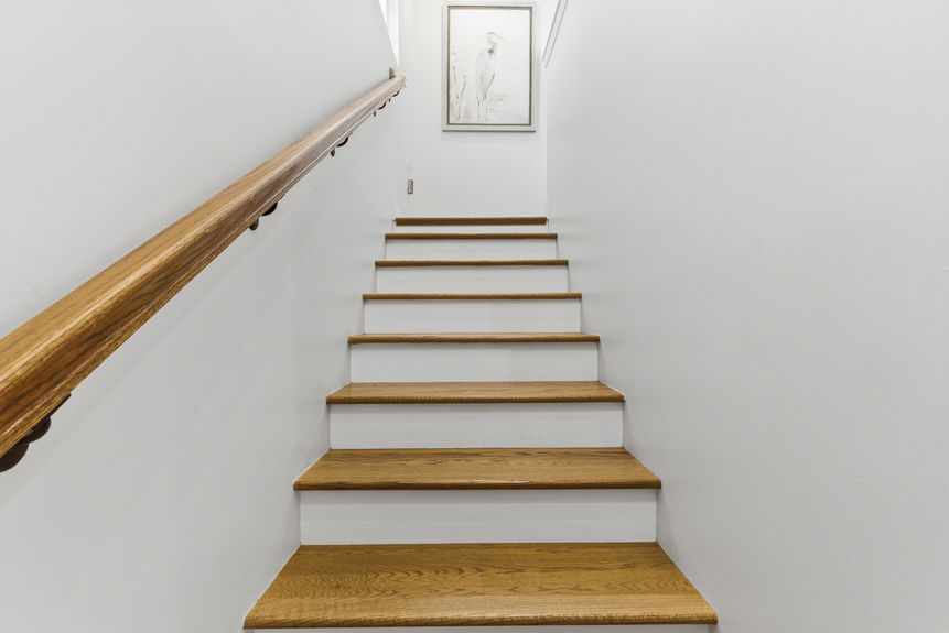 Interior view of a home entryway featuring a brown-and-white patterned accent wall, a gold geometric lamp on a white console table, and a decorative runner rug leading to a white interior door.