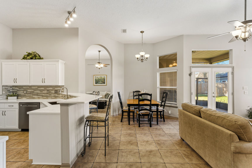 Homes for Sale in St. Johns, Florida: A formal dining area with a six-chair table set, neutral tile flooring, and a view toward the front entryway with a white door and transom window.