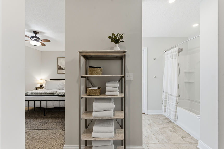 Modern bathroom with a double sink white vanity, large mirror with bell-shaped lights, and a white sliding pocket door leading into a carpeted walk-in closet.