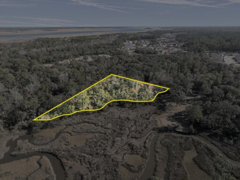 Aerial photo with a yellow boundary outline showing the shape and size of a vacant lot on Pine Island Road, bordering the marsh.