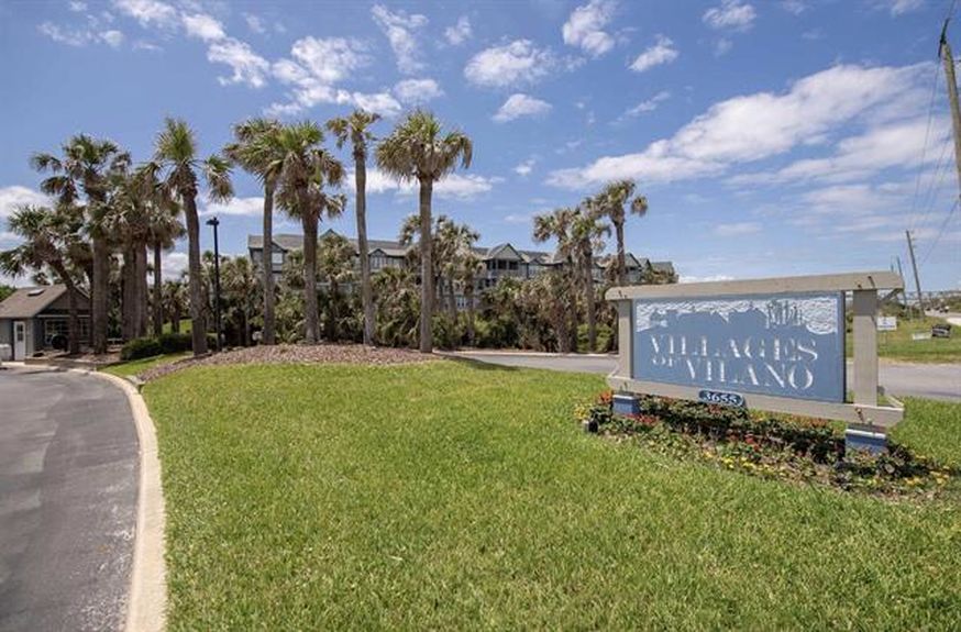 The prominent blue and white "Villages of Vilano" monument sign at the landscaped entrance of this gated waterfront community in St. Augustine, Florida.