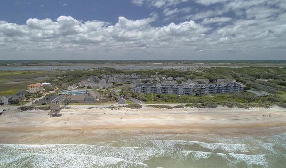 An aerial perspective of the gated Villages of Vilano community in St. Augustine, Florida, showing the residential layout nestled between the Atlantic Ocean beachfront and the serene inland marsh landscape.