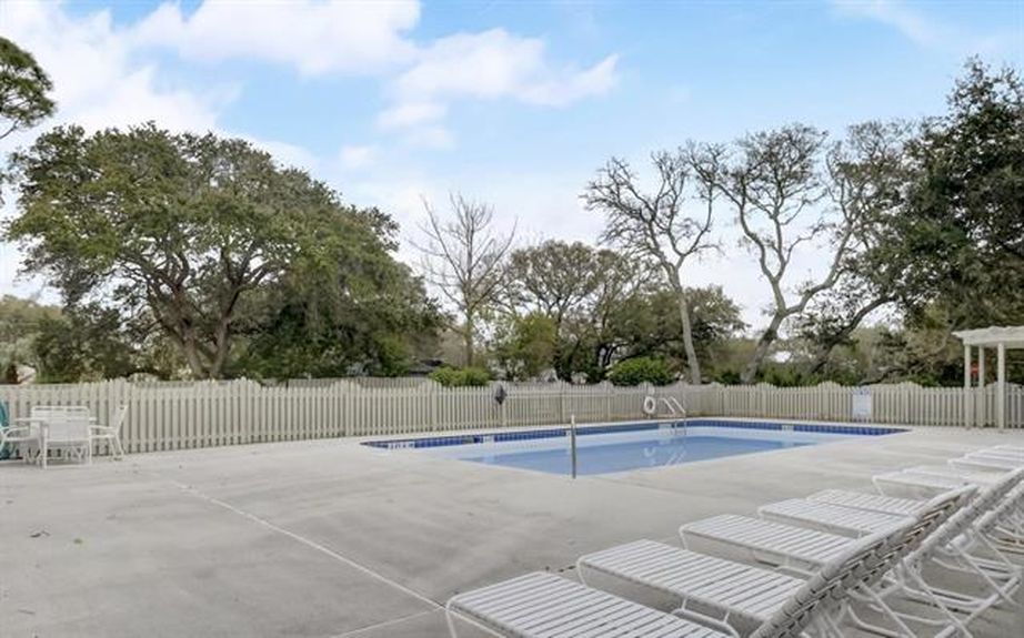 A pristine outdoor swimming pool surrounded by a spacious sundeck and lounge chairs in the gated Villages of Vilano neighborhood in St. Augustine.
