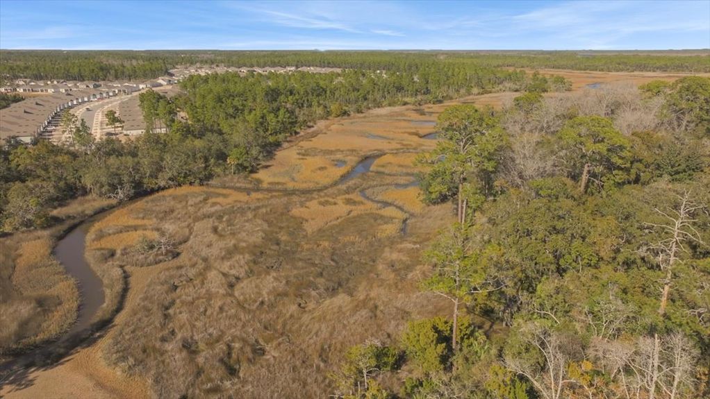 Low-altitude drone shot gliding over the golden marsh grass and tidal creek, emphasizing the peace and quiet of the location.