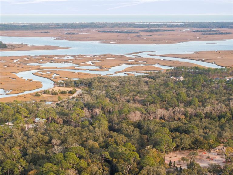 Telephoto aerial shot focusing on the winding blue channels of the salt marsh leading out to the open water of the Intracoastal.