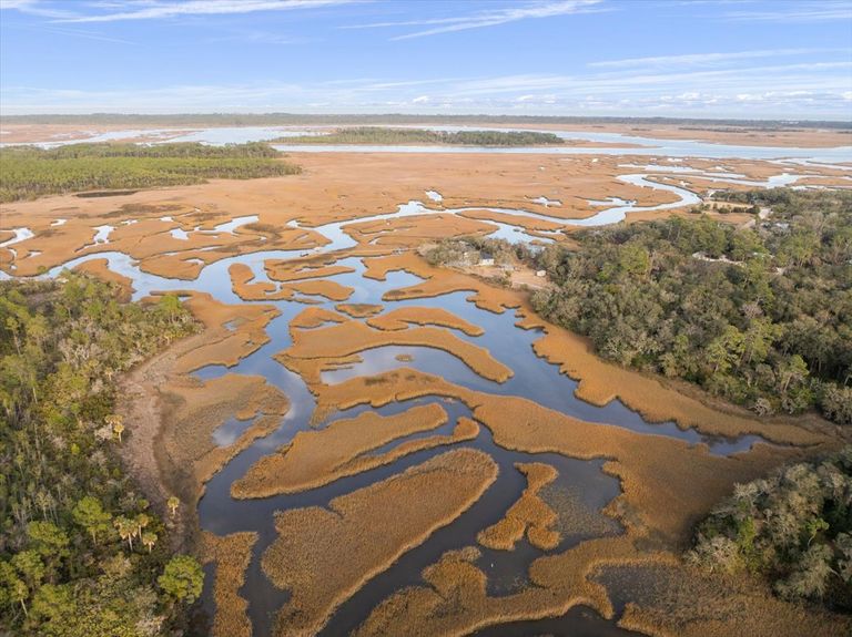 Aerial landscape shot of the intricate patterns of the salt marsh and tidal creeks in Ponte Vedra, bathed in soft sunlight.