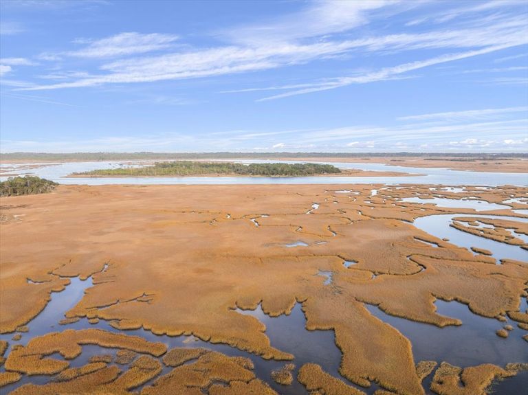 Expansive aerial view looking east over the marsh towards the Intracoastal Waterway and the Atlantic Ocean barrier islands in the distance.