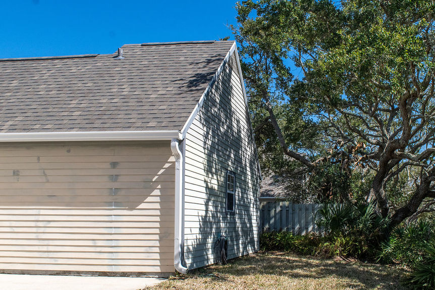 Side view of 364 Village Dr showcasing the recently replaced roof and mature trees in the gated Villages of Vilano neighborhood.