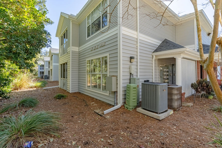 Side exterior of the grey-sided condo building at 35103 Harbour Vista Cir showing HVAC units and green landscaping.